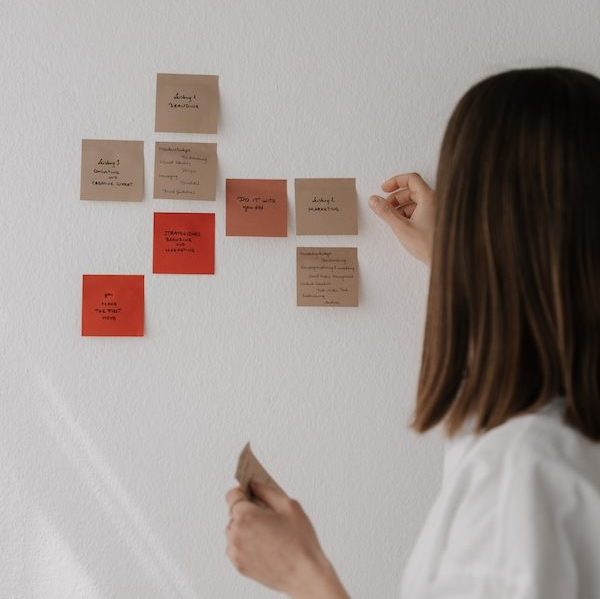 Judith von you did steht an der Wand und klebt Post Its zu Strategie an die Wand